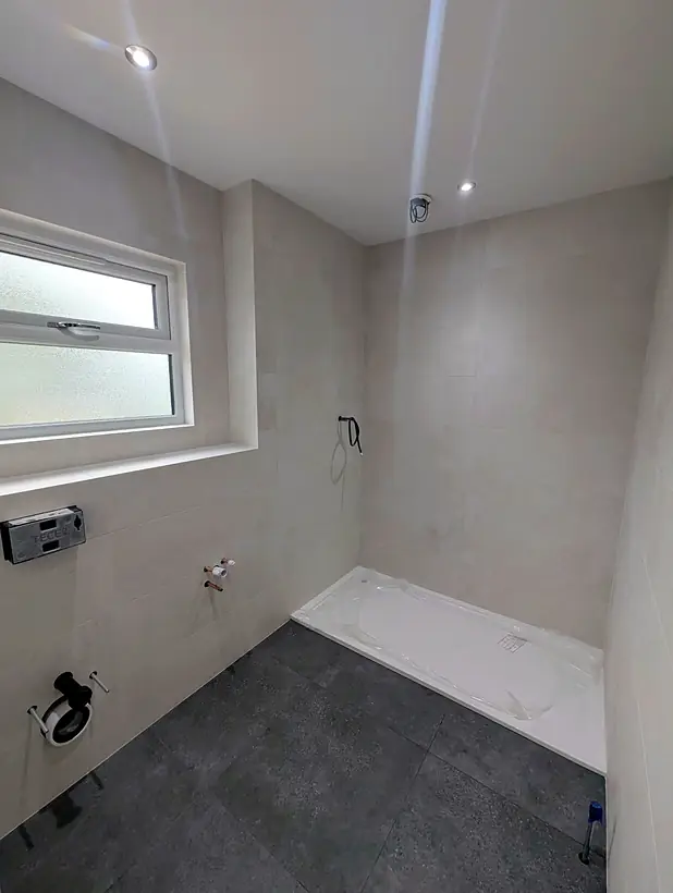 Bathroom with light walls, dark floor and tiled window reveal