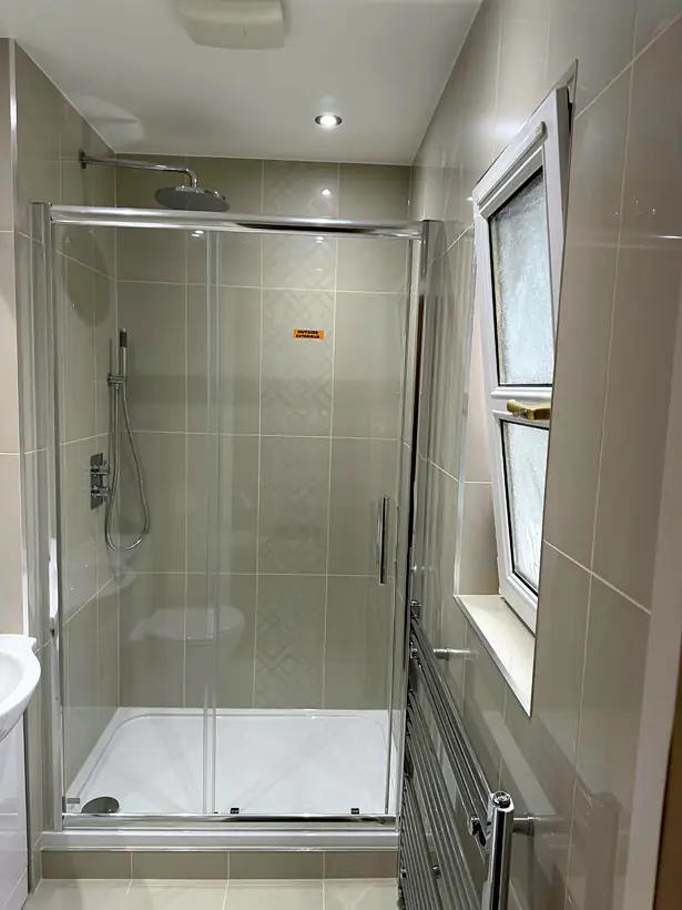 Tiled shower enclosure with patterned feature tiles and rain shower